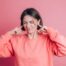 femme portant un pull decontracte sur fond couvrant les oreilles avec les doigts avec une expression agacee pour le bruit de la musique forte 2