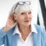 close up elegant stylish elderly woman in formal suit having hearing problems, holding hand at her ear, trying to hear you, saying: speak louder, please. age, maturity, people and health concept